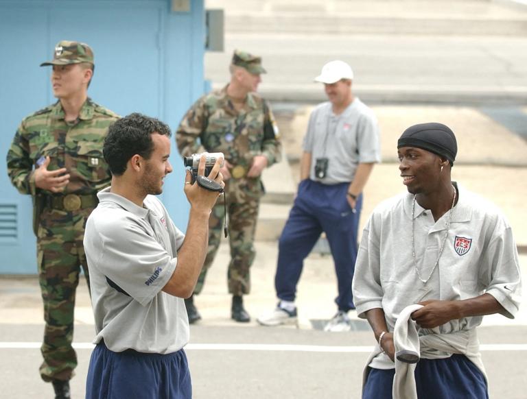 Landon Donovan (L) uses a video camera to record his teammate DaMarcus Beasley (R) as he and other teammates of the US national soccer team visit the de-militarized zone in Panmunjon 31 May 2002. Reyna and most of the team visited the zone marking the frontier between North and South Korea some 50 miles north of Seoul. The US soccer squad will face Portugal, South Korea and Poland in the first round of the 2002 FIFA Korea-Japan World Cup. AFP PHOTO Roberto SCHMIDT (Photo by ROBERTO SCHMIDT / AFP) (Photo by ROBERTO SCHMIDT/AFP via Getty Images)