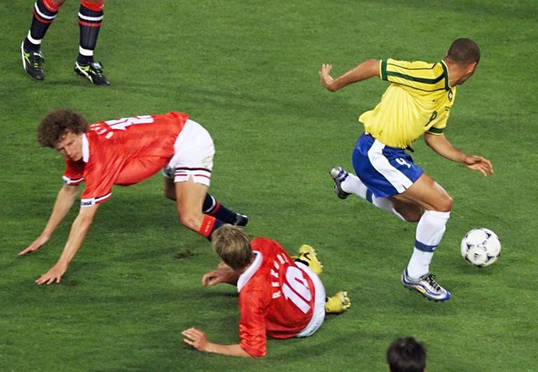 Brazilian forward Ronaldo (R) passes by Norwegian defender Dan Eggen (L) and midfielder Kjetil Rekdal (#10) as they fall down 23 June at the Stade Velodrome in Marseille, south of France, during the 1998 Soccer World Cup Group A first round match between Brazil and Norway.
(ELECTRONIC IMAGE) AFP PHOTO GEORGES GOBET (Photo by GEORGES GOBET / AFP) (Photo by GEORGES GOBET/AFP via Getty Images)